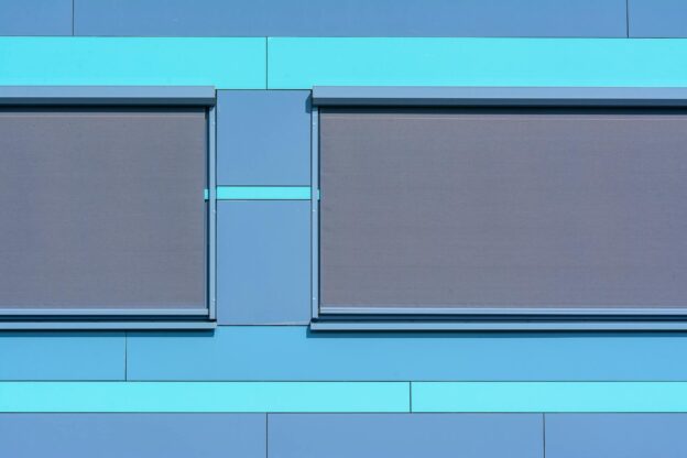 Minimalist blue facade featuring modern roller blinds for architectural appeal.